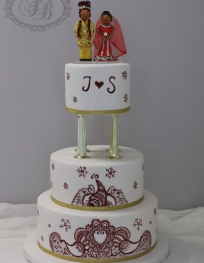 Red painted paisley wedding cake with pillars and topper