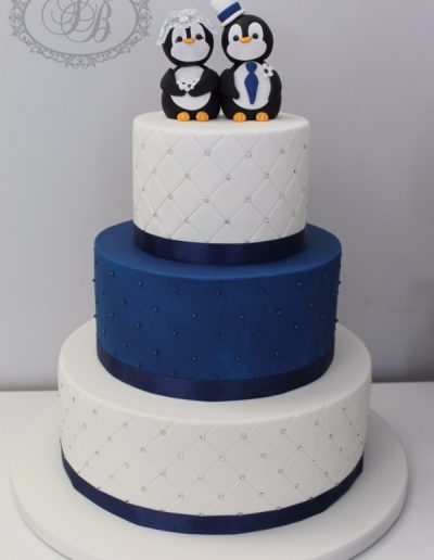 Blue and white quilted wedding cake with penguin topper