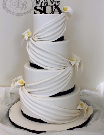4 tier wedding cake with white drapes and lillies
