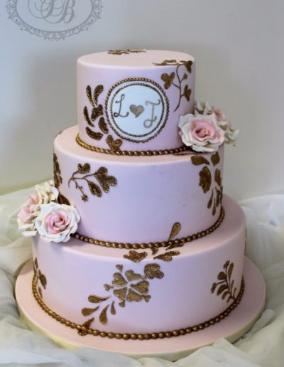 Pink wedding cake with gold piping, monogram and sugar roses