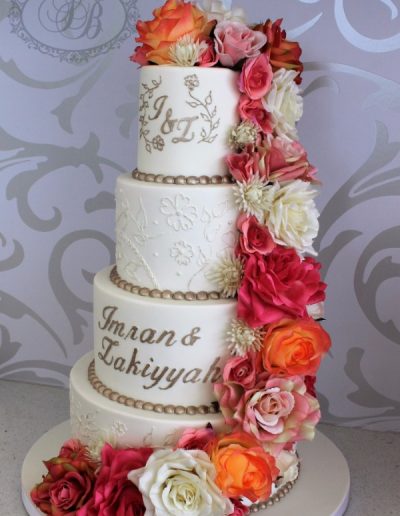 Champagne and white wedding cake with pink and orange flower cascade
