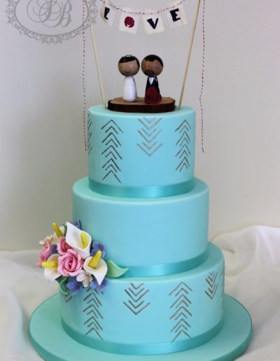 Blue wedding cake with gold painted arrows and craft topper