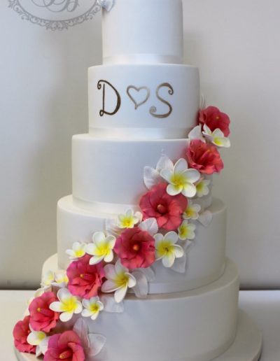 5 tier white wedding cake with silver monogram, sugar frangipani and hibiscus cascade