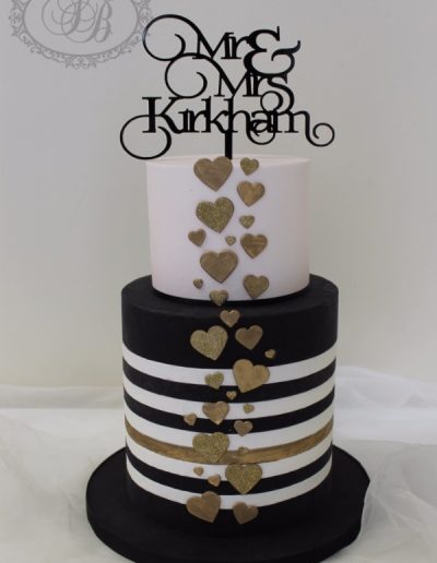 Black and white striped wedding cake with pink and gold hearts