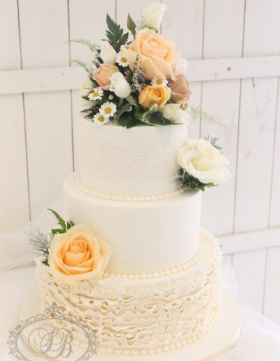 3 tier ivory wedding cake with ruffles and fresh apricot flowers