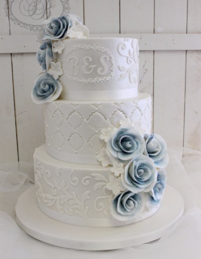 White pearled damask wedding cake with blue sugar flowers