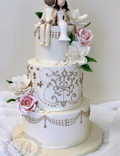 Ivory wedding cake with gold painted piping, sugar flowers and couple topper