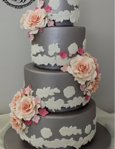Grey 4 tier wedding cake with applique lace and peach sugar flowers