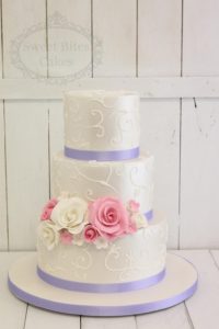 Wedding cake with piping and purple ribbon